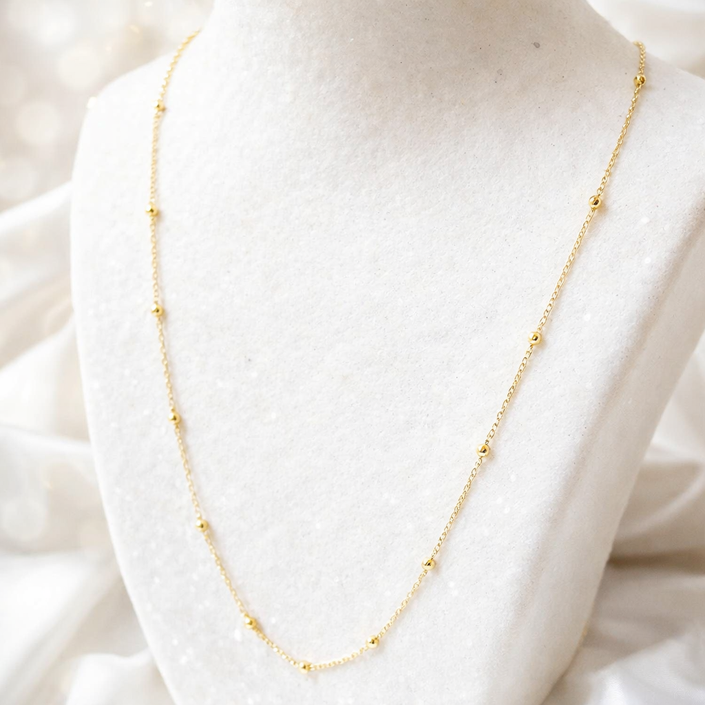 Chaîne à boules en or massif 750 portée autour du cou, collier fin avec boules espacées.
