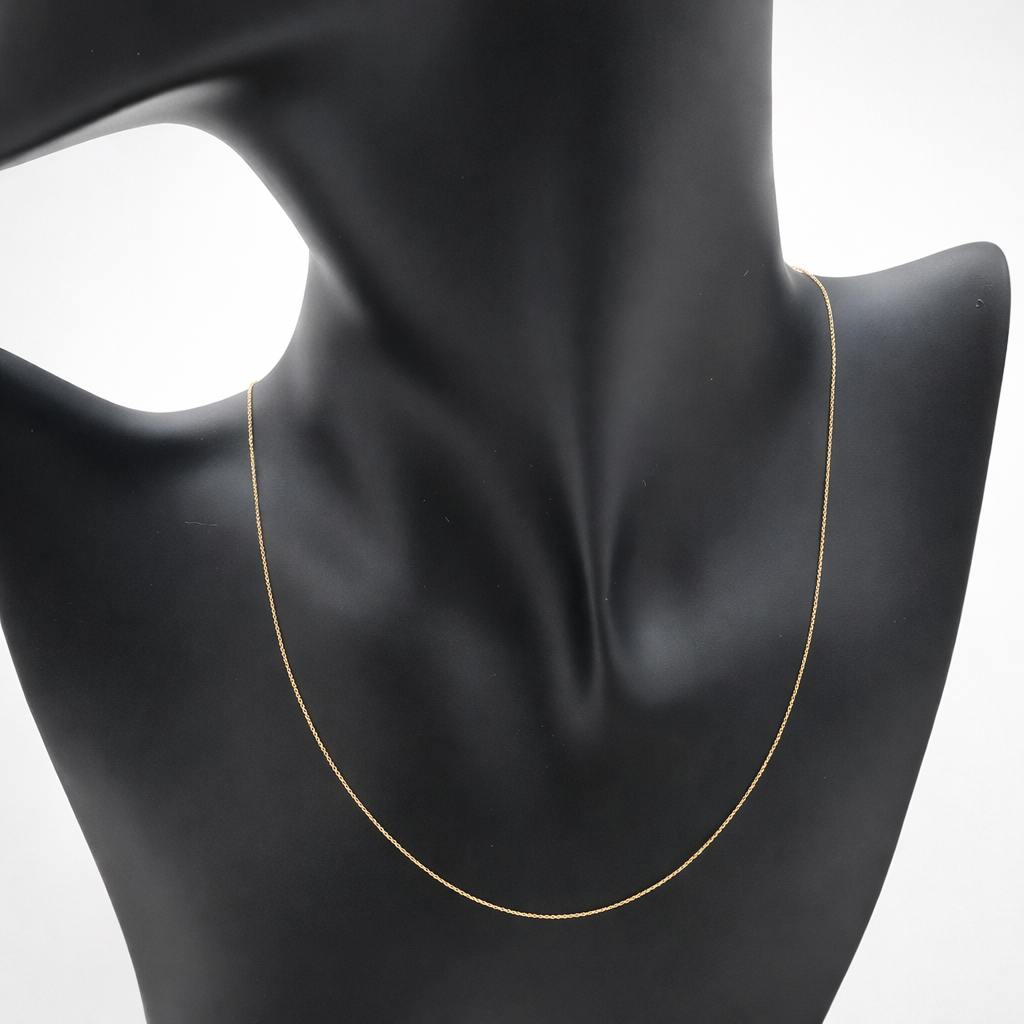 Chaîne fine maille forçat en or massif 18 carats 750 portée sur buste noir, mettant en valeur l’or jaune poli.