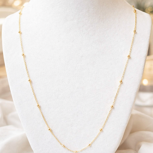 Collier boule en or massif 18K porté sur buste, maille à boules fines montrant le tombé du collier.