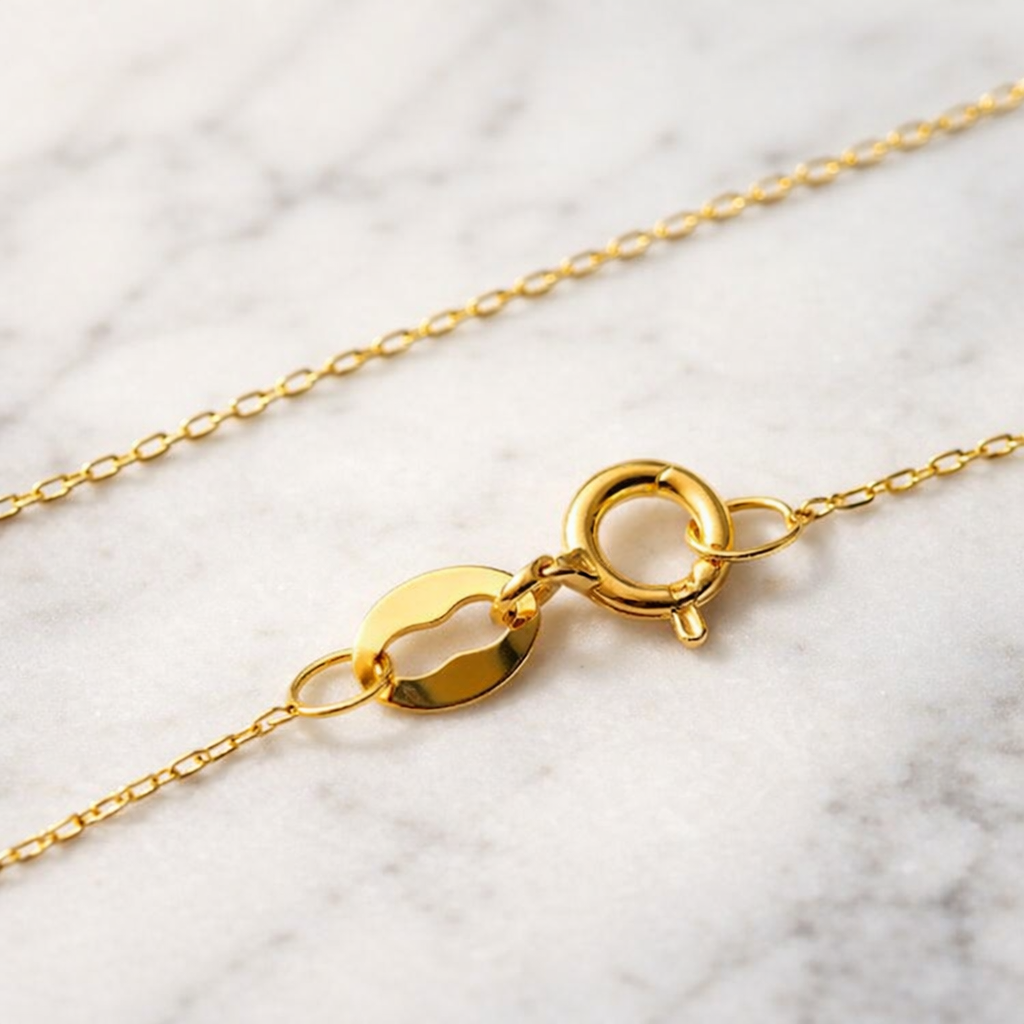 Gros plan du fermoir anneau ressort d’une chaîne fine maille forçat en or massif 18 carats 750.