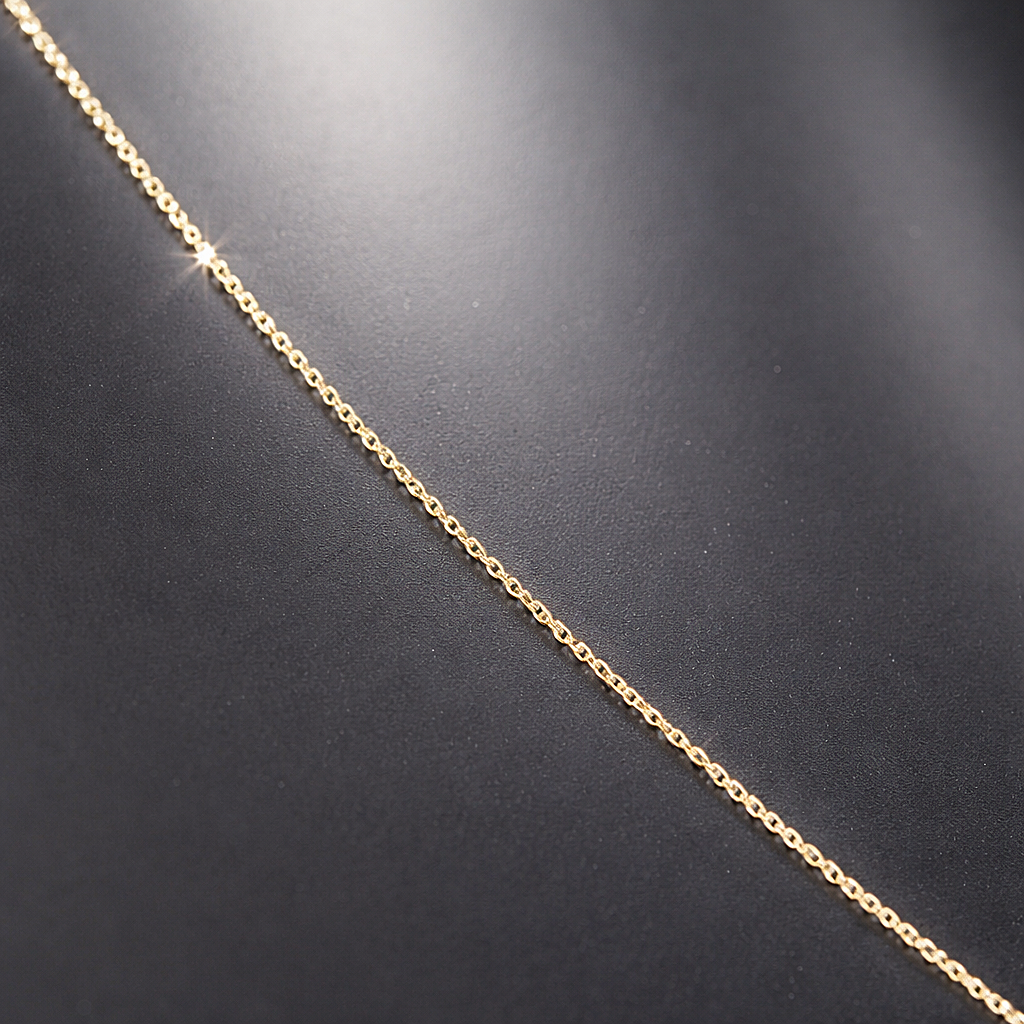 Gros plan sur la maille forçat fine en or massif 18 carats 750, finition lisse et régulière.