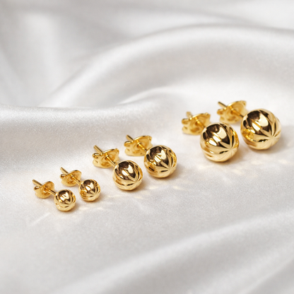 Puces d’oreilles boules ciselées en or massif 18 carats 750 présentées en plusieurs tailles.
