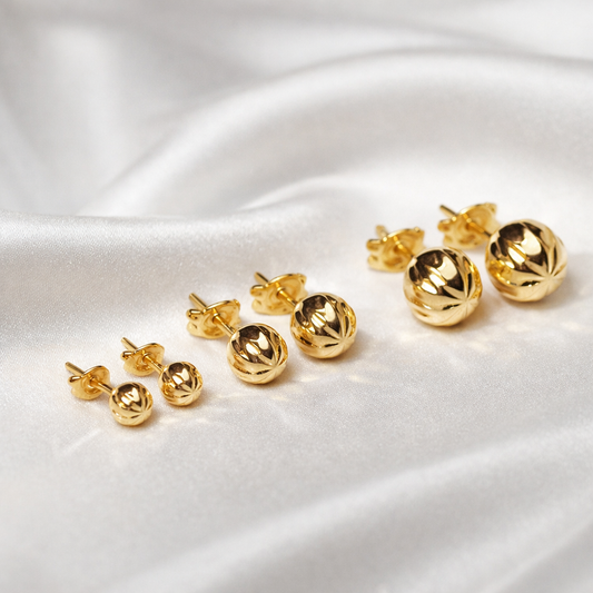 Puces d’oreilles boules ciselées en or massif 18 carats 750 présentées en plusieurs tailles.