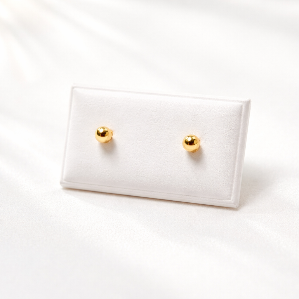 Paire de puces d’oreilles boule en or massif 18 carats 750 en or jaune poli sur support blanc.