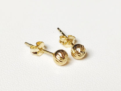 Détail de boucles d’oreilles boules ciselées en or massif 18 carats 750, finition or jaune poli.