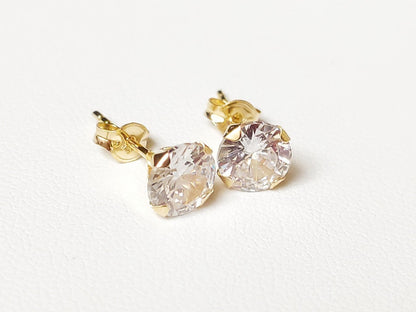 Détail de boucles d’oreilles puces en or massif 18 carats 750 avec pierre ronde transparente.