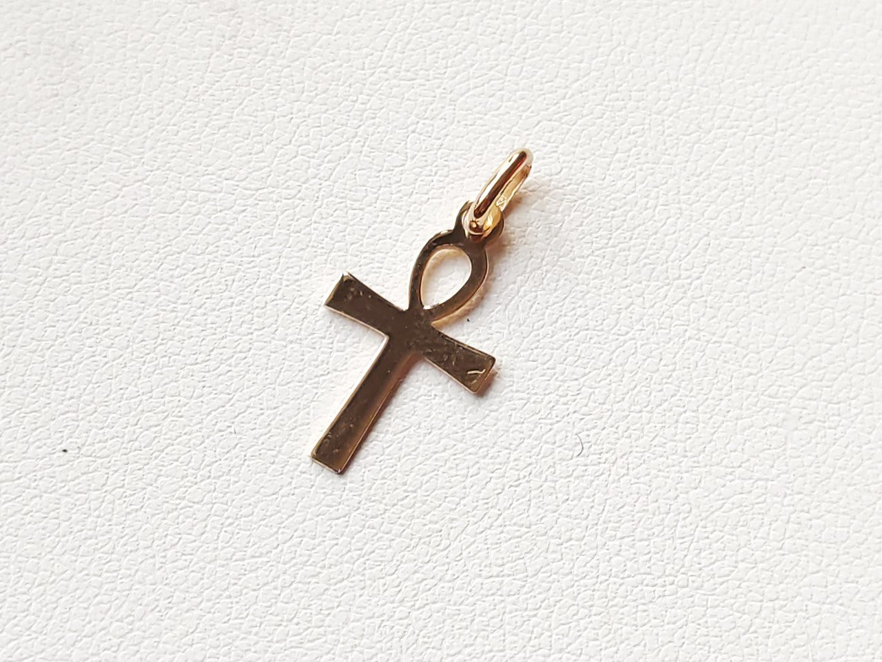 Pendentif croix égyptienne Ankh en or massif 18 carats 750 posé à plat, montrant la forme et les reliefs.