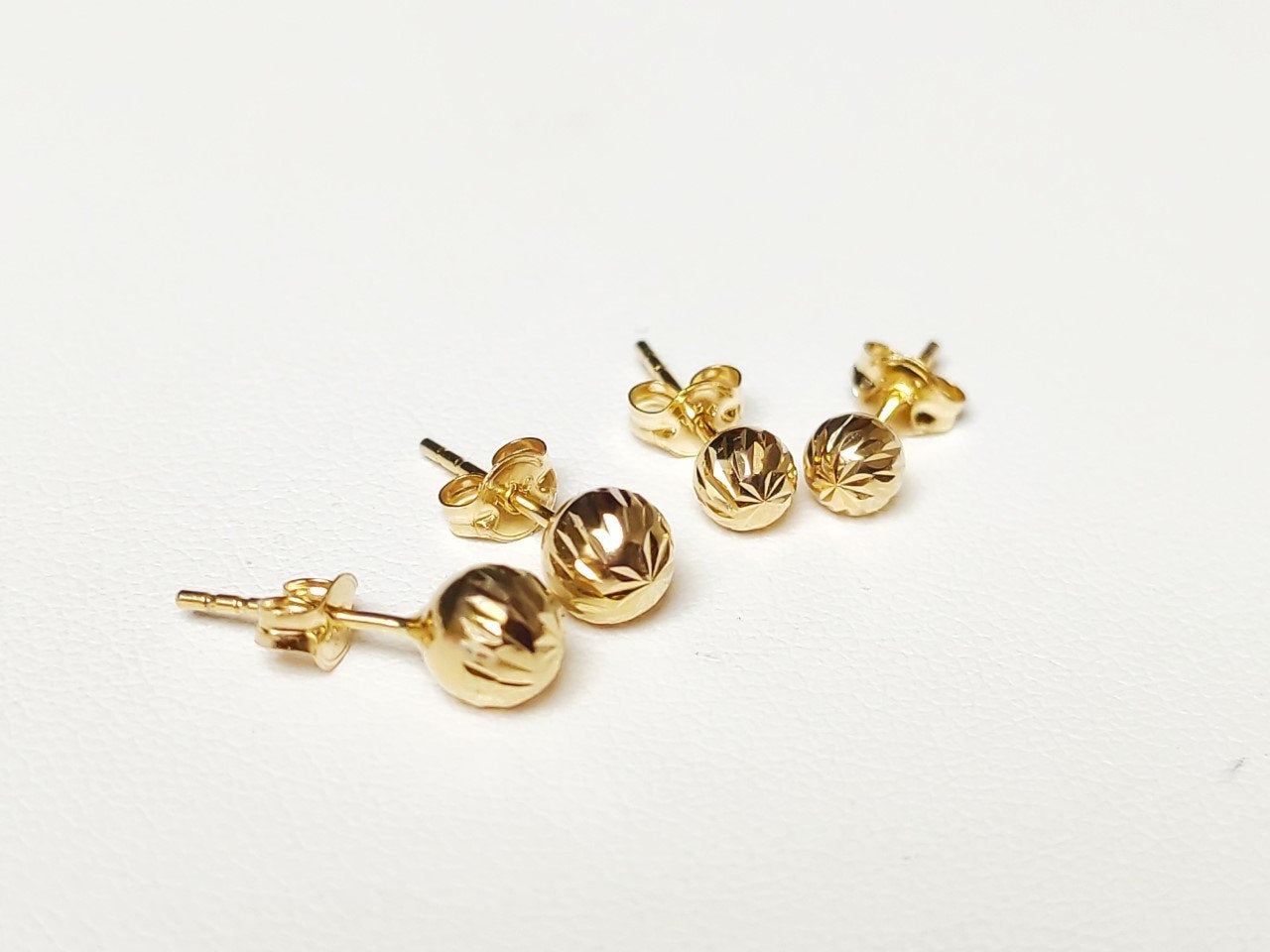 Puces d’oreilles boules facettées en or massif 18 carats 750 vues de côté, montrant la tige.