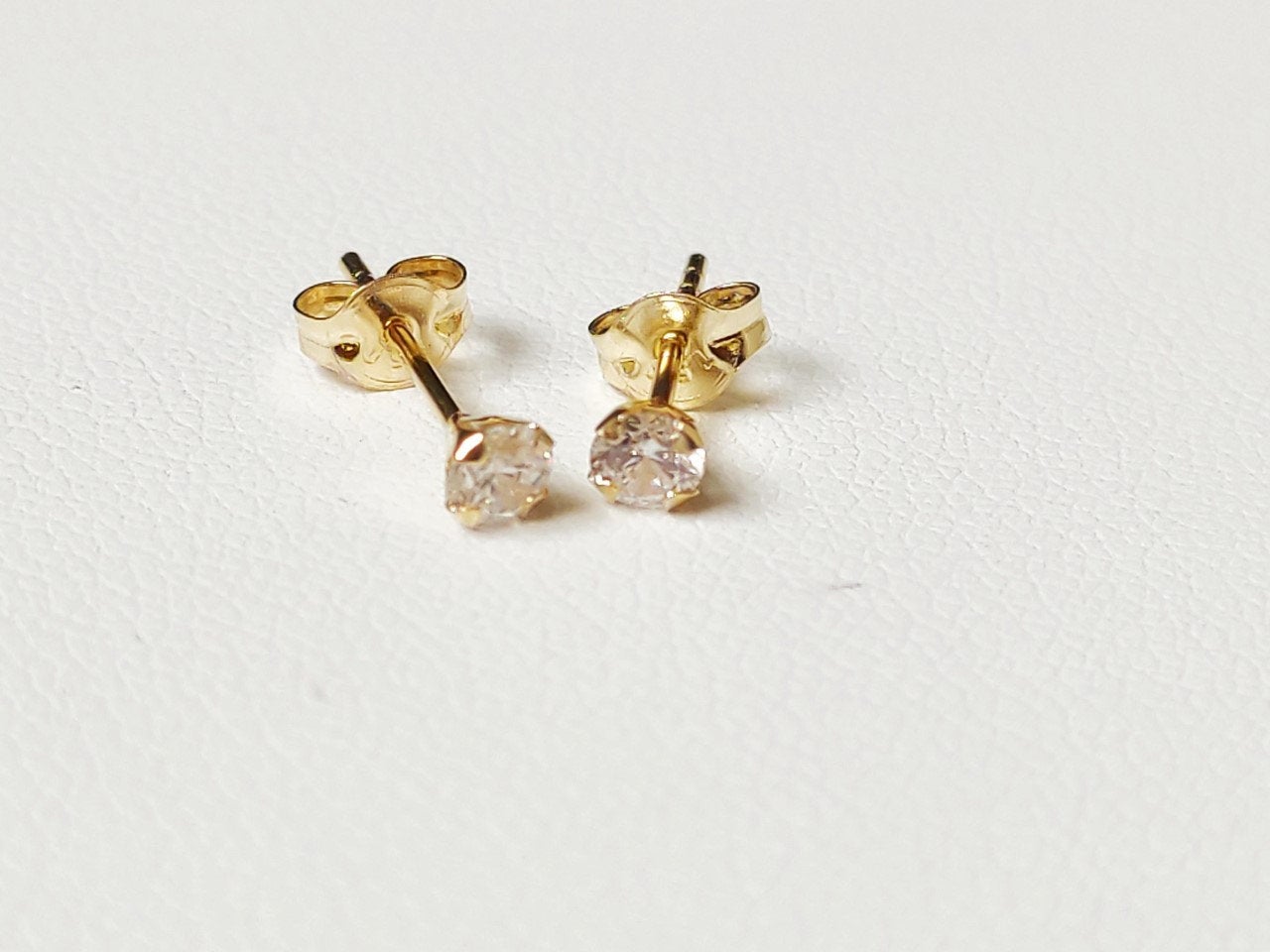 Paire de puces d’oreilles en or massif 18 carats 750 avec pierre ronde transparente vue de face.